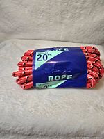 Coiled bright red rope with black markings wrapped with a blue label indicating length and rope type.