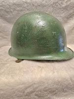 Angle view of the helmet showing green paint, scratches, and textured surface