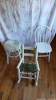 All three white furniture pieces arranged together: wicker stool, children's rocking chair, and small wooden chair.