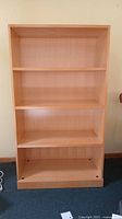 Front view of a light wood four tier shelf unit showing four deep shelves and smooth finish.