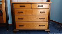 Front view of wooden 5 drawer dresser showing drawer fronts and handles