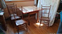 Set of dining table with four wooden chairs placed around it in room with hardwood floor