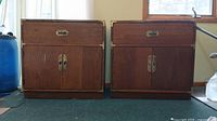 Pair of medium-brown wood cabinets with drawer and double-door lower storage, front view. Left cabinet shows rusting hardware and wear.