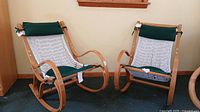 Pair of wooden hammock-style rocking chairs facing forward, showing white woven net seat and back with attached green padded cushions on the headrest.