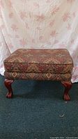 Front view of the rectangular ottoman showing patterned upholstery and claw feet.