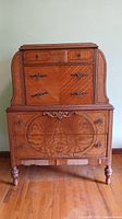 Front view of vintage wooden dresser with five drawers and roll-top desk on top.