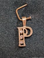 Close-up image of 10KT gold pendant shaped as letter 'P' with four small diamonds in vertical row