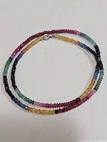 Full view of the multicolored faceted gemstone necklace laid in a circular shape showing the gradient colors.