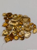 Photo showing a collection of assorted citrine gemstones in various cuts and sizes, displaying a range of yellow to golden hues.