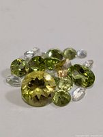 Photo showing assorted faceted gemstones in green, yellow, and clear colors, various sizes and cuts.