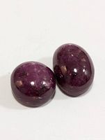 Two polished star ruby cabochons featuring purplish-red color and visible inclusions.