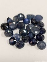 Close-up of multiple genuine blue sapphire gemstones showing various cuts and blue hues.