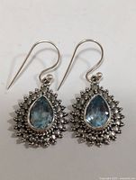Front view of both silver earrings with blue topaz stones to show overall design and condition.