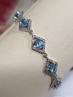 Close-up photo showing the linked diamond shapes with blue topaz and CZ settings in sterling silver.