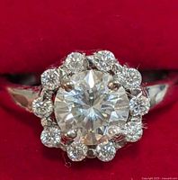 Front view close-up showing the central round moissanite gemstone surrounded by a halo of smaller stones set in silver.