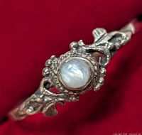 Close-up front view showing the round white moonstone center with ornate silver detailing on the ring band.