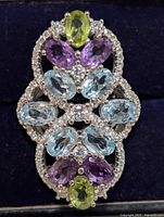 Front view of the sterling silver multi gemstone ring showing blue topaz, amethyst, and peridot stones with clear accent stones in an intricate design.
