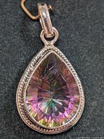 Close up front view of pear-shaped mystic topaz set in decorative silver bezel pendant.