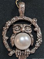 Front view of the silver owl pendant showing detailed owl design and pearl center on a dark background.