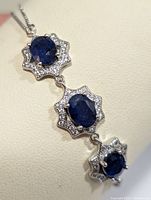 Close-up photo of the triple linked sapphire and cubic zirconia sterling silver bracelet showing the deep blue oval sapphire stones each surrounded by clear cubic zirconia stones in a flower-like setting.