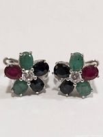 Front view of one earring showing arrangement of sapphire, ruby, emerald stones with central diamond.