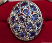 Top view of silver ring with multiple oval faceted tanzanite stones arranged in a cluster showing the design and color of stones.
