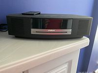 Front view of Bose Wave Music System showing CD slot, speaker grilles and remote on top