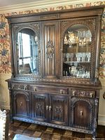Full front view of wooden glass display cabinet with ornate carved wood and glass doors showing glass shelves inside.