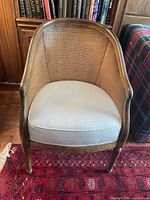 Front view of barrel chair showing cane back and upholstered seat cushion