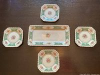 Full set of one rectangular serving platter and four matching small plates on wood surface. Items show vintage crazing and used condition.