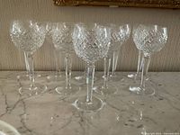 Six glasses arranged in two rows on a marble surface under a framed painting.
