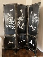 Full view of the black lacquered folding screen showing the panels and mother-of-pearl inlay artwork.