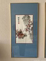 Framed embroidered fabric art with birds and blossoms, shown full view.