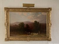 Full view of gilded frame, landscape painting and brass picture light mounted above