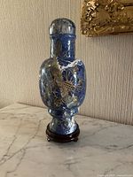 Front and side views of the blue marble vase with gold floral detailing on wooden stand, showing shape and design clearly.