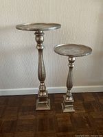 Two metal decorative stands side by side showing size difference and overall design.