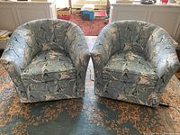Photo of both swivel bucket chairs side by side on patterned area rug near window