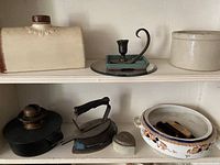 Two shelves containing miscellaneous vintage and antique household items including ceramics, metalware, and collectibles.
