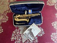 Alto saxophone and accessories arranged inside open hard-shell case
