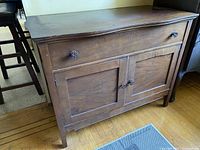 Full cabinet view showing wood grain, drawer with drawer knobs, and double door with two door knobs.
