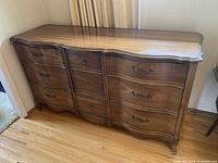 Full view of vintage Dixie brand wooden dresser showing scalloped curved front and wood grain finish.