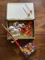 Open box displaying two small gold Toledo letter openers, one large Toledo letter opener with red handle, two ceramic castanets with painted horsemen inside box.