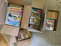 Four cardboard boxes filled with regular Archie comic books and Archie Digest magazines, showing spines and top covers with colorful comic artwork.