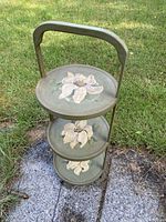 Full view of the vintage 3 tier plant stand on grass showing design and structure