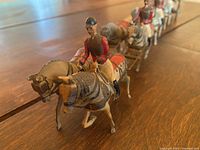 Frontal view showing the horses and riders in red uniforms attached to the coach.