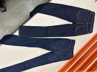 Two pairs of dark blue denim women's jeans laid flat showing full length and back pockets.