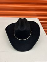 Black felt cowboy hat with wide brim and creased crown, silver-tone braided band detail.
