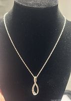 Full view of silver chain necklace displayed on a black velvet bust showing the twisted rope chain and infinity-shaped pendant with crystals.