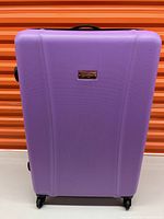 Front view of a purple hardcase suitcase with four spinner wheels and black handle.
