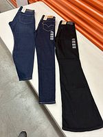 Three pairs of Levi's jeans laid side by side in blue and black shades, showing size tags and Levi's leather patches